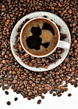 Closeup of white cup of coffe on roasted coffe beans background © Sebastian