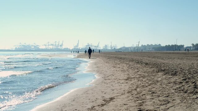 People walk along sandy beach of Valencia. Spain