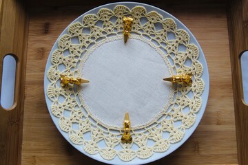 Brass cheese markers on plate with cotton doily 