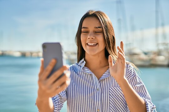 Young hispanic girl smiling happy doing video call using smartphone at the port