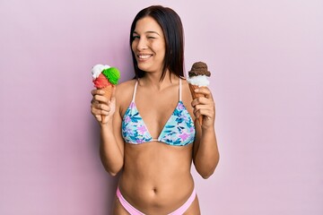 Young latin woman wearing bikini holding ice cream winking looking at the camera with sexy...