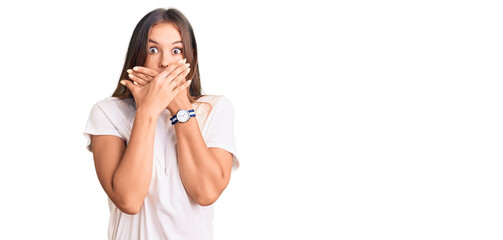 Beautiful caucasian woman wearing casual white tshirt shocked covering mouth with hands for...