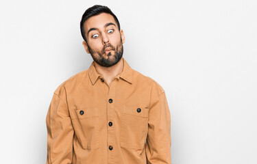 Young hispanic man wearing casual clothes making fish face with lips, crazy and comical gesture. funny expression.