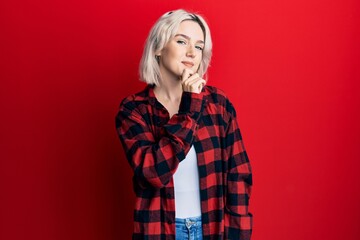 Young blonde girl wearing casual clothes smiling looking confident at the camera with crossed arms and hand on chin. thinking positive.