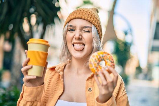 Young blonde girl smiling happy having breakfast at the city.