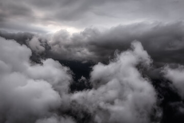 Cloudscape Background. Beautiful and striking aerial view of the puffy clouds. Dramatic Dark Art Render. Taken over the mountains from airplane near Vancouver, British Columbia, Canada.