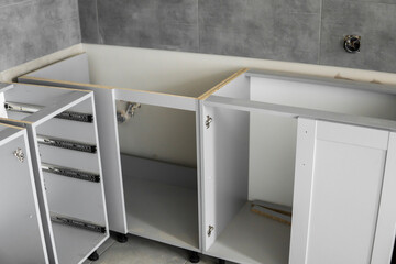 Stainless telescopic bayonet drawer slide guides, installed on a kitchen cabinet from gray...