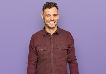 Obraz premium Young hispanic man wearing casual clothes winking looking at the camera with sexy expression, cheerful and happy face.