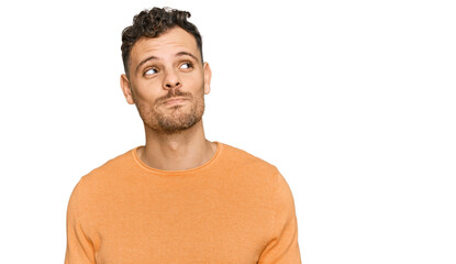 Young hispanic man wearing casual clothes smiling looking to the side and staring away thinking.