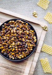 Alternative medicine bee bread ( fermented flower and plant pollen by honey bees) pellets on plate. Beeswax cera alba and bee figurines for decoration vintage jute cloth.