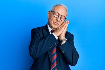 Senior caucasian man wearing business suit and tie sleeping tired dreaming and posing with hands together while smiling with closed eyes.