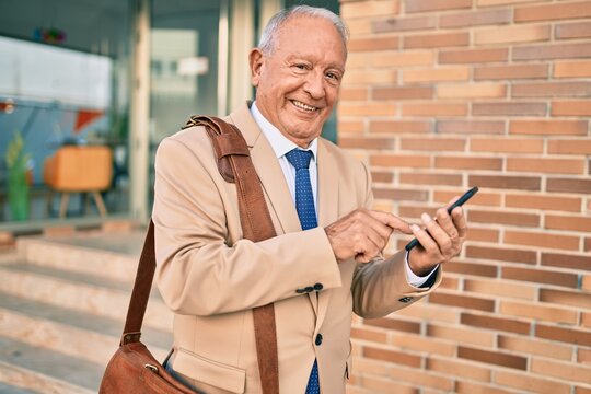 Senior grey-haired businessman smiling happy using smartphone at the city.