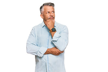 Middle age grey-haired man wearing casual clothes with hand on chin thinking about question, pensive expression. smiling with thoughtful face. doubt concept.