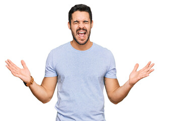 Naklejka premium Young hispanic man wearing casual clothes celebrating mad and crazy for success with arms raised and closed eyes screaming excited. winner concept