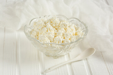 Cottage cheese in a glass bowl. On a white wooden table
