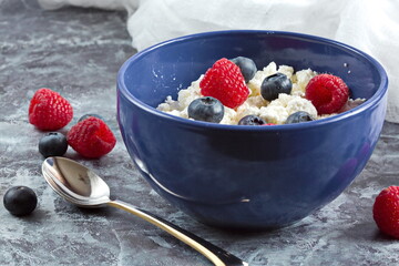 Blue bowl with fresh red ripe strawberries and blueberries and natural cottage cheese, on white wooden table for fitness breakfast. Dietary product. The concept of healthy eating.