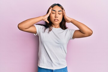 Young latin woman wearing casual white tshirt with hand on head, headache because stress. suffering migraine.