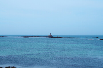 small lighthouse on rock in calm blue ocean. Brittany France