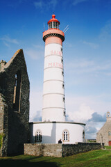 white and red lighthouse and ancient church, Brittany, France