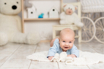 happy baby boy lies at home in the children's room with toys, development concept and games