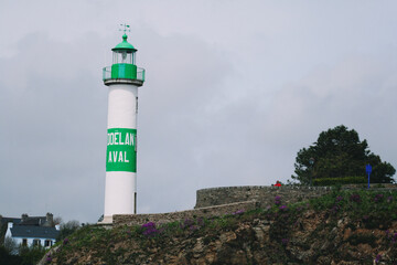 Fototapeta na wymiar white and green lighthouse with village. Brittany, France
