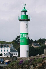 white and green lighthouse with village. Brittany, France