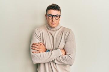 Hispanic young man wearing casual turtleneck sweater shaking and freezing for winter cold with sad...