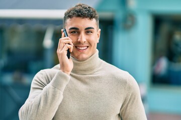 Young hispanic man smiling happy talking on the smartphone at the city.