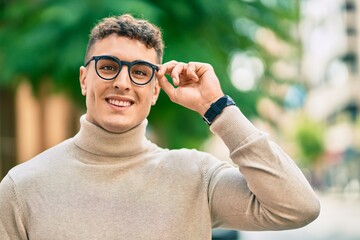 Young hispanic man smiling happy wearing glasses at the city.