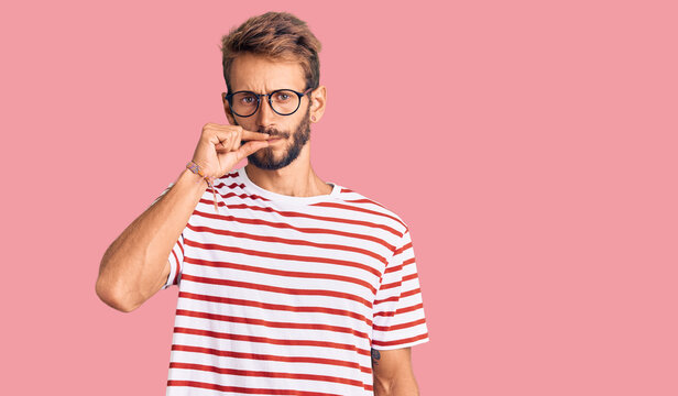Handsome blond man with beard wearing casual clothes and glasses mouth and lips shut as zip with fingers. secret and silent, taboo talking