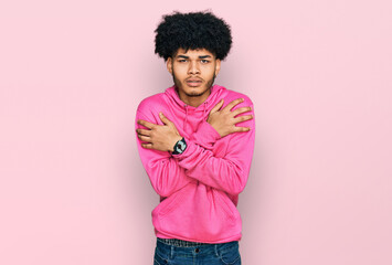 Young african american man with afro hair wearing casual pink sweatshirt shaking and freezing for winter cold with sad and shock expression on face
