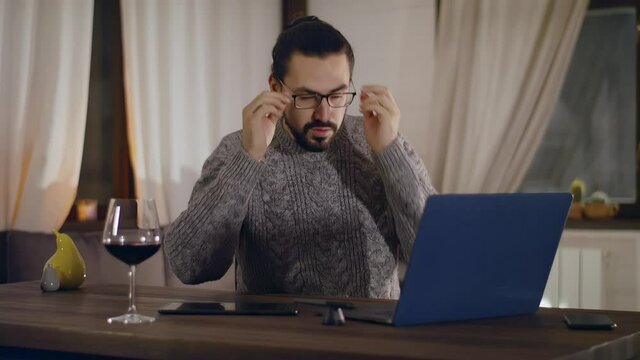A person in glasses works on a laptop