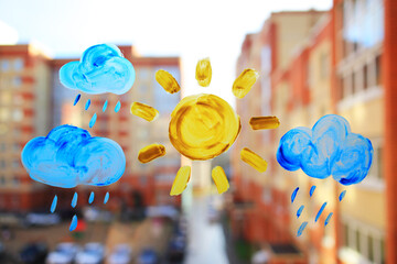 Drawing on the window with paints with a city background. Clouds and the sun are painted on the...