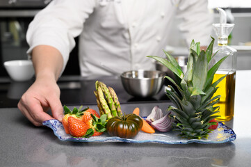 Male Chef Hands Holding plate with vegetables and Fruit. Chef Cooking Healthy Vegetables, fine organic dining. Dieting Culinary Food. High quality photo