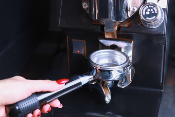 in the female hand is a coffee holder, the coffee beans are poured into the filter and the funnel background is blurred