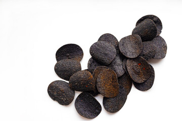 Black chips with activated charcoal and red pepper in a white bowl on a white background, top view. Unhealthy food, fast food.