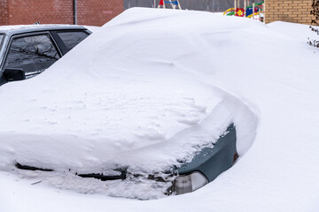Cars in the parking lot near a residential building buried under the snow. Huge winter snowdrifts....