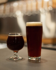 2 dark beers sitting on a bar top in a local bar brewery taproom