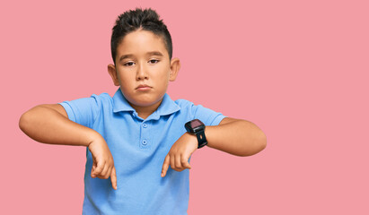 Little boy hispanic kid wearing casual clothes pointing down looking sad and upset, indicating direction with fingers, unhappy and depressed.