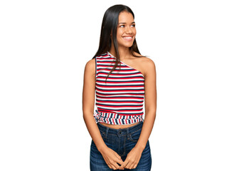 Fototapeta premium Beautiful hispanic woman wearing casual clothes looking away to side with smile on face, natural expression. laughing confident.