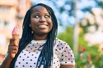 Young african american woman smiling happy eating ice cream at the city.