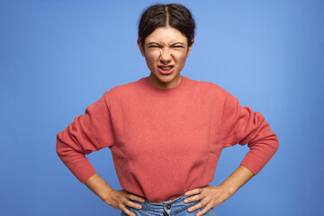 What did you say, huh? Studio image of quarrelsome gnarly young woman with nose ring making angry grimace, holding hands on waist, going hard on you for mistake, being in bad mood. Negative emotions