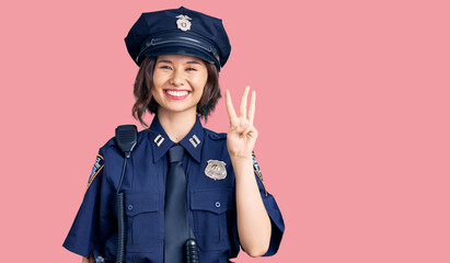 Young beautiful girl wearing police uniform showing and pointing up with fingers number three while smiling confident and happy.