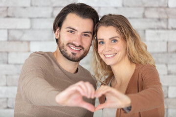 portrait of a happy young couple showing love gesture