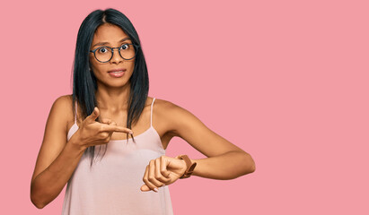 Young african american woman wearing casual clothes and glasses in hurry pointing to watch time,...