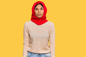 Young african american woman wearing traditional islamic hijab scarf relaxed with serious expression on face. simple and natural looking at the camera.