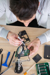 close-up of a human hand repairing smartphone with screwdriver