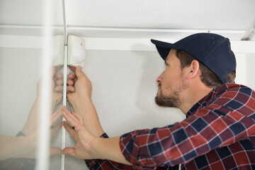 technician installing smoke detector at the corner