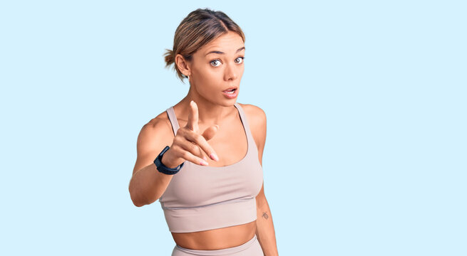 Beautiful caucasian woman wearing sportswear pointing displeased and frustrated to the camera, angry and furious with you