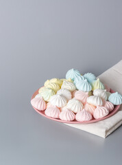Sugar protein dessert in pastel colors in a pink plate on gray background. Linen napkin. The vertical frame. Copy Space